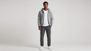 Male model showing a three-layer athleisure outfit with base layer, heavyweight tee, and fleece hoodie, paired with joggers and white sneakers