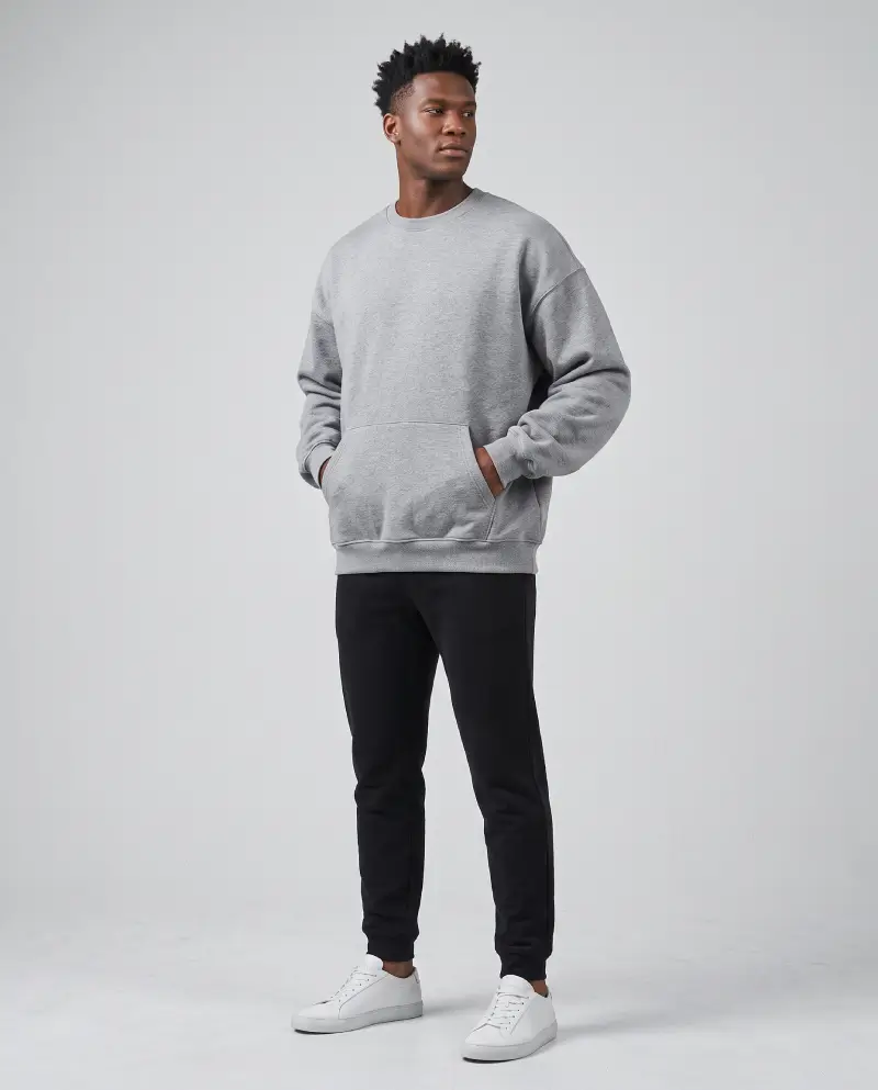 Full-body shot of a male model wearing an oversized sweatshirt solo with joggers and white sneakers, streetwear look