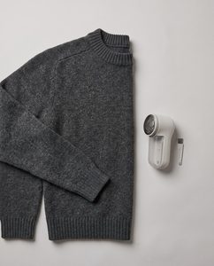 Overhead flat-lay of a sweater laid flat with a fabric shaver, sweater care scene