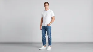 Full-body shot of a male model wearing tapered jeans with cuffed ankles, a heavyweight tee, and sneakers, smart-casual look